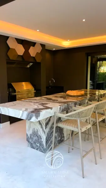 Grey veined stone is used for the dining table, alongside a golden glow and contrasting dark finishes.