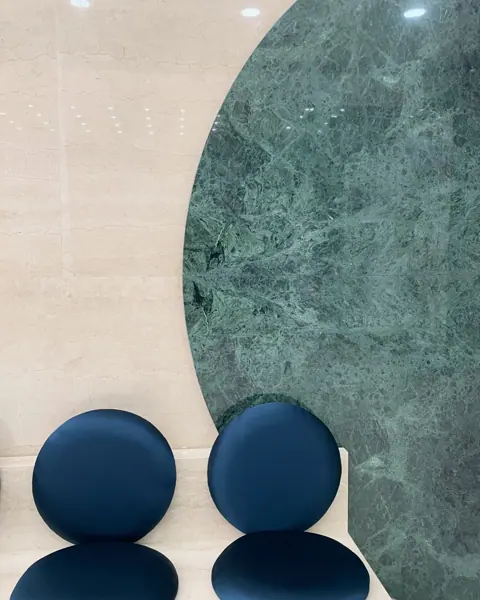 Green and white natural stone is used for the decorative screen and seating area, alongside comfortable seating and a restrained neutral palette.