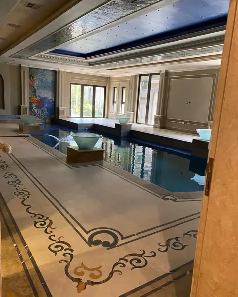 Warm beige natural stone is used for the floor throughout the room, alongside contrasting borders and a carefully composed floor pattern.