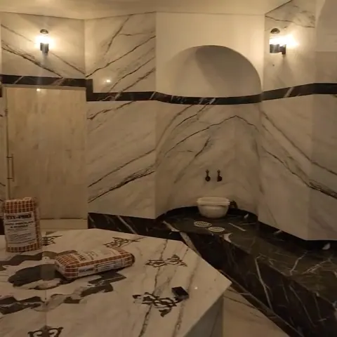 White marble with grey veining is used for the bathroom walls and floor, alongside contrasting borders and a carefully composed floor pattern.