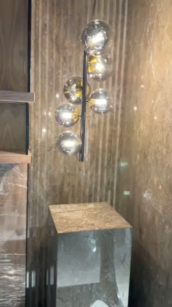 Rich brown veined stone is used for the vanity and its surrounding surfaces, alongside pendant lights and simple cabinetry.