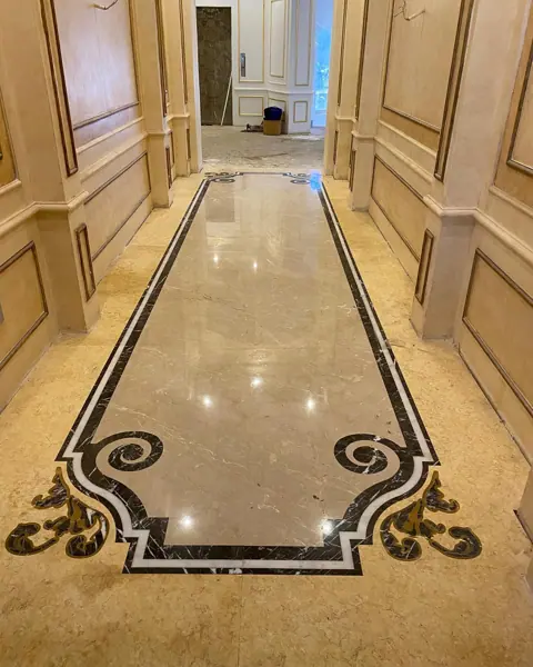 Warm beige natural stone is used for the corridor floor, alongside contrasting borders and a carefully composed floor pattern.