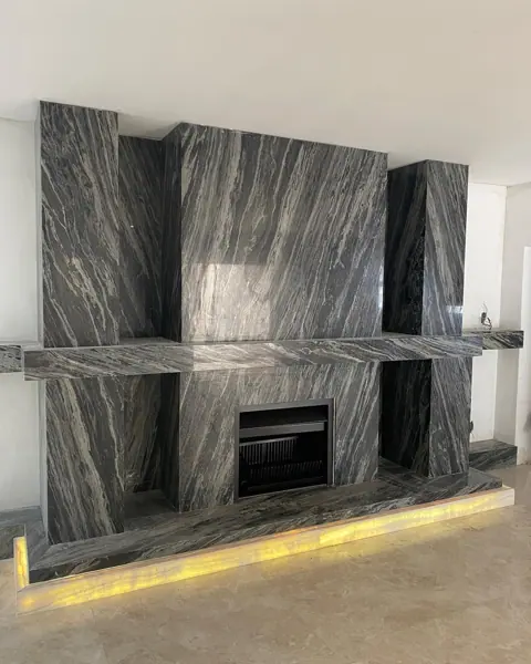Stone with mirrored veining is used for the fireplace surround, alongside a golden glow and contrasting dark finishes.