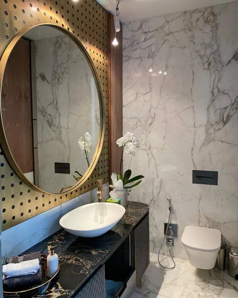 White marble with grey veining is used for the vanity and its surrounding surfaces, alongside ornate mirrors and traditional decorative details.
