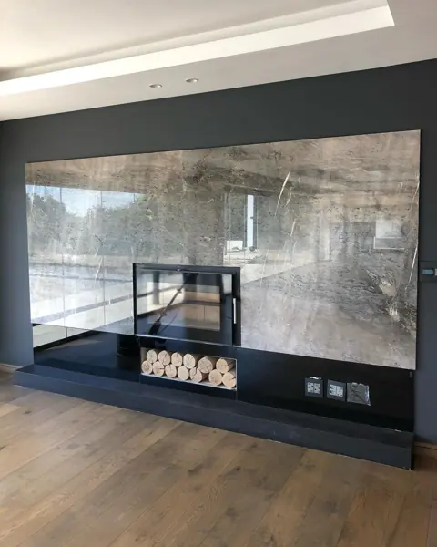 Grey veined stone is used for the fireplace surround, alongside light cabinetry and warm timber finishes.