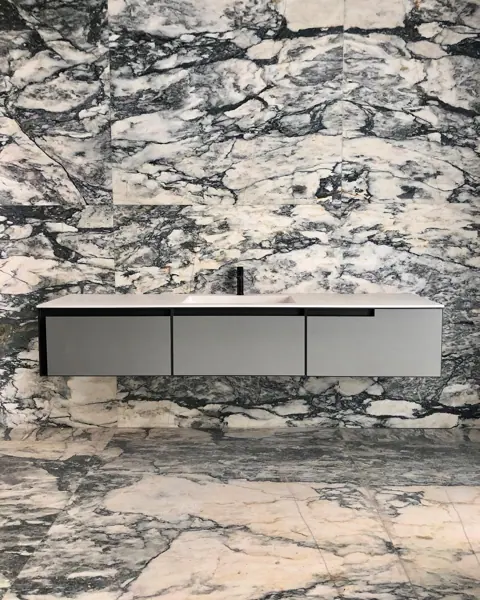 Violet and cream veined stone is used for the vanity and its surrounding surfaces, alongside light cabinetry and warm timber finishes.