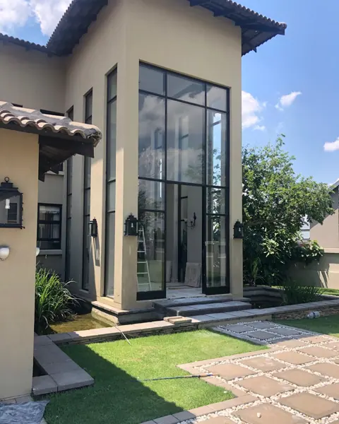 Warm beige natural stone is used for the exterior walls and entrance, alongside garden views and relaxed outdoor seating.