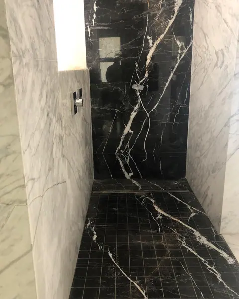 Black marble with white veining is used for the shower walls, alongside clean architectural lines and contemporary fittings.