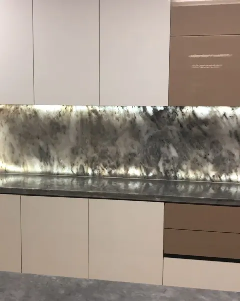 Grey veined stone is used for the kitchen countertop and splashback, alongside light cabinetry and warm timber finishes.