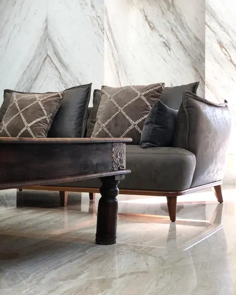 Stone with mirrored veining is used for the feature wall, alongside comfortable seating and a restrained neutral palette.