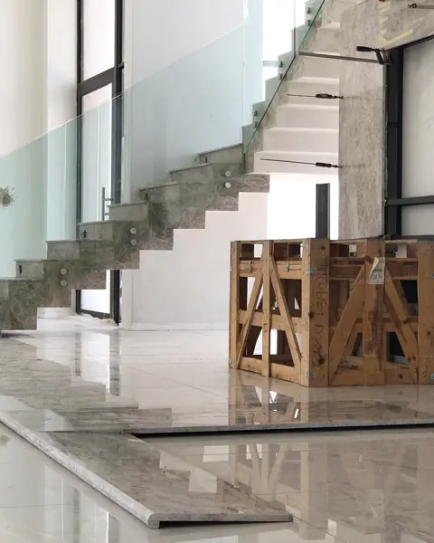 Grey veined stone is used for the stair treads and landings, alongside glass balustrades and generous daylight.