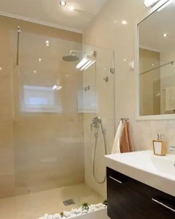 Warm beige natural stone is used for the shower walls, alongside clean architectural lines and contemporary fittings.