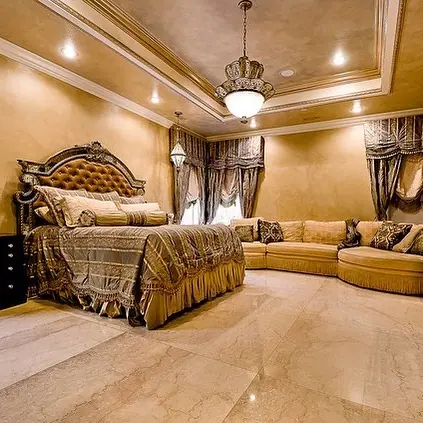 Warm beige natural stone is used for the floor throughout the room, alongside ornate mirrors and traditional decorative details.