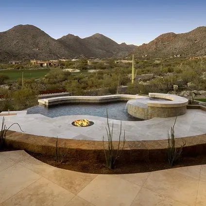 Warm beige natural stone is used for the poolside terrace, alongside broad glazing and an expansive distant view.