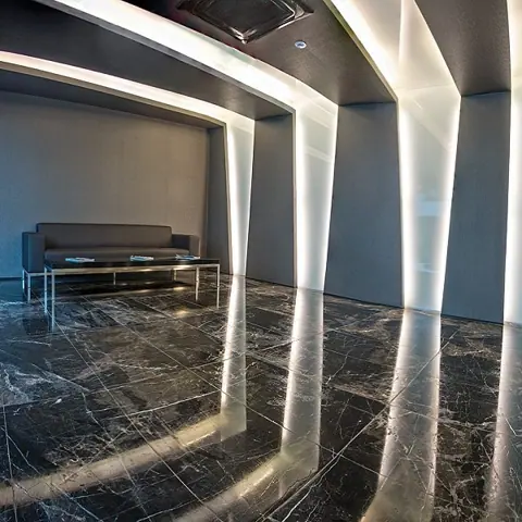 Black marble with white veining is used for the floor throughout the room, alongside a golden glow and contrasting dark finishes.