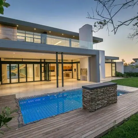 Pale veined stone is used for the exterior walls and entrance, alongside garden views and relaxed outdoor seating.